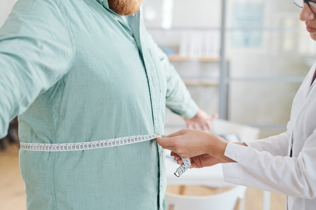 Doctor measuring obese man stomach