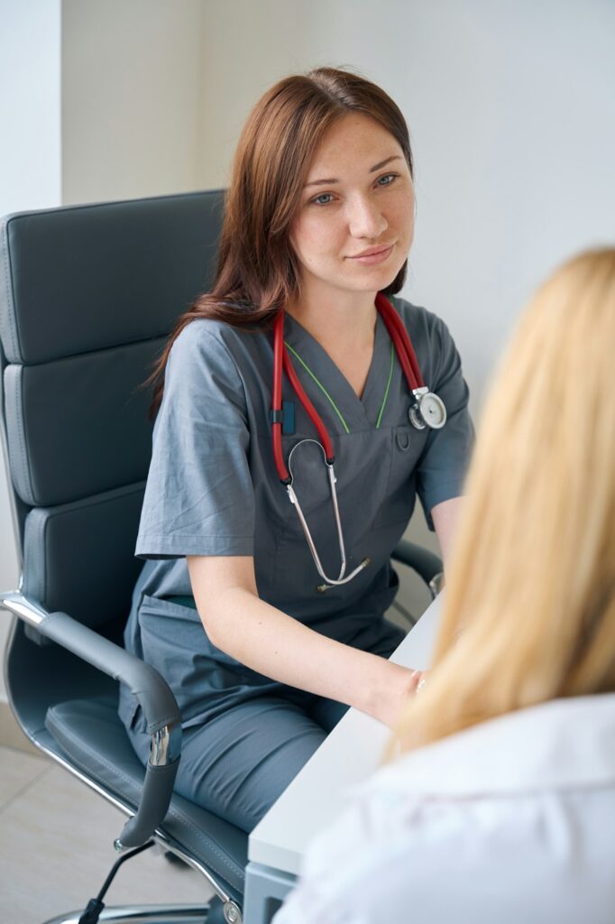 Qualified family doctor communicating with client during medical consultation