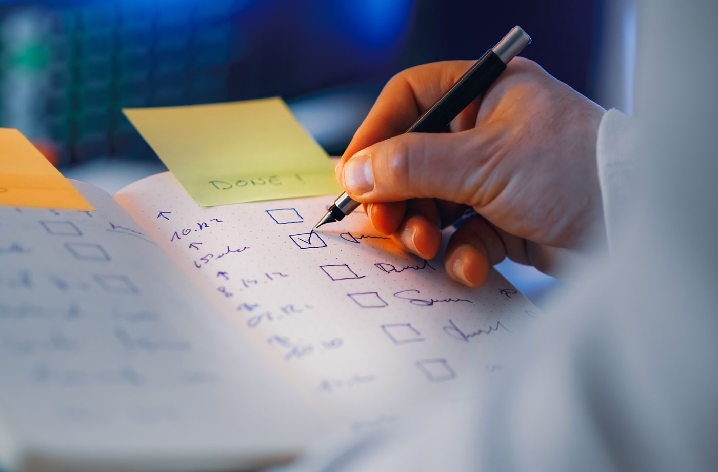 A hand using a pen to mark a checklist in a notebook.
